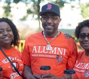 Three individuals in orange Buffalo State alumni t-shirts