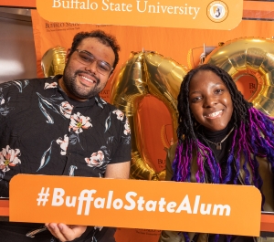 Commencement students holding an alum sign